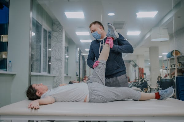 Физический терапевт выполняет растяжку пациентке для профилактики контрактур