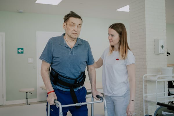 Пациент с ходунками занимается с физическим терапевтом в клинике реабилитации