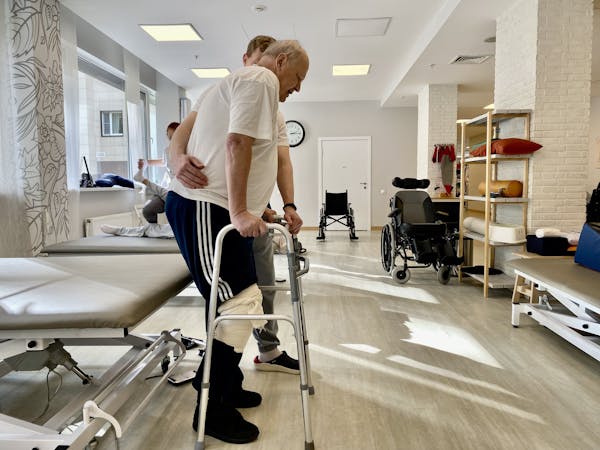Пожилой пациент после инсульта занимается с физическим терапевтом